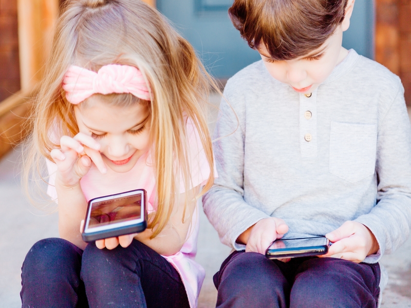 Dečak i devočica koriste mobilni telefon